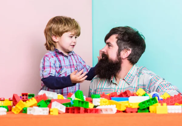 Every dad and son must do together. Dad and kid build plastic blocks. Child care development and upbringing. Father son game. Father and son create constructions. Bearded man and son play together