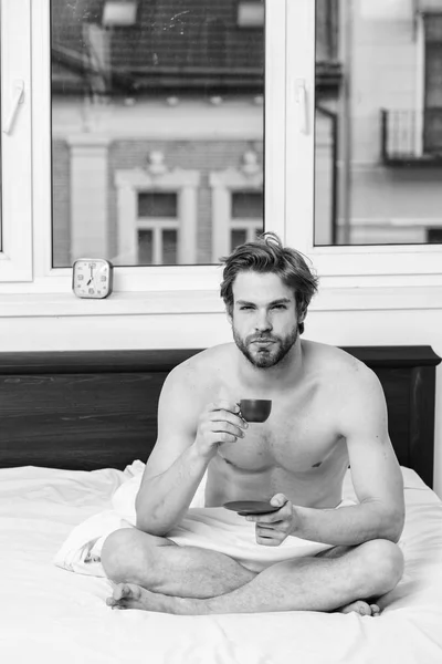 El café te llena de energía. Cada mañana con su café. Empieza bien el día. Cómo el café afecta su cuerpo desde el primer sorbo. Hombre guapo macho con torso muscular relajante en la cama con taza de café — Foto de Stock