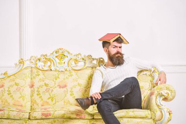 Maço kafasına, çatı gibi açık kitap ile oturuyor. Adam, öğretmen öğretim ile overdid, deli profesör oldu. Kavramı çok. Sakal ve bıyık oturur kanepe, beyaz duvar arka plan üzerinde olan adam