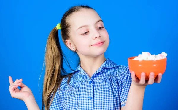Meisje glimlachende gezicht houden kom snoep marshmallows in de hand blauwe achtergrond. Een meisje met lang haar eet snoep en traktaties. Snoept de enige ware liefde. Zoetekauw concept. Calorie en dieet — Stockfoto