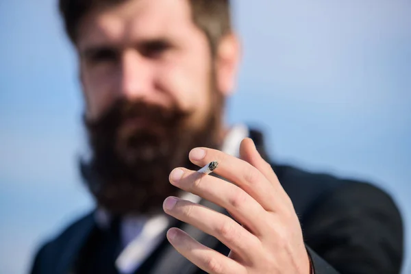 Cigarettes help us with everything from boredom to anger management. Bearded hipster smoking cigarette sky background. Guy cigarette enjoy nicotine influence. Man with beard mustache hold cigarette