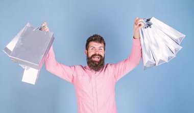 Şık sakal ve bıyık alışveriş çantaları taşırken olan adam. Lüks butik hediye sertifikası üzerinde mavi arka plan izole galibi. Neşeli yüzü, mutluluk kavramı ile pembe gömlekli sakallı adam