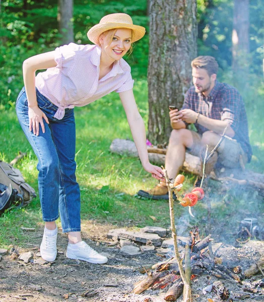 Girl in straw hat cooking food at campfire nature background. Tips every camper should know about campfire cooking. Camping tips. Easy tips to Improve your campfire cooking. Foods to cook on stick