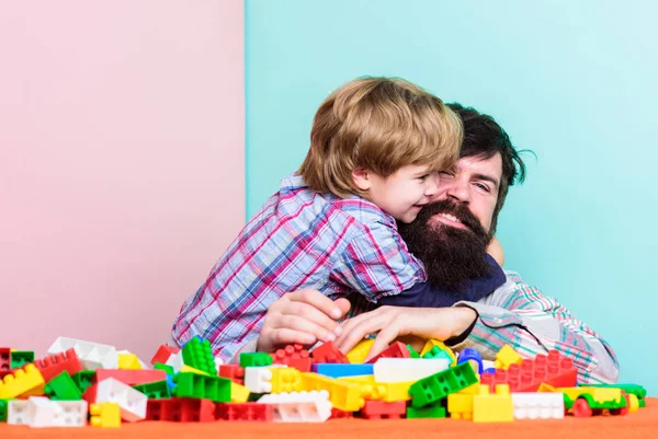 Father and son create constructions. Bearded man and son play together. Surefire ways to bond with your son. Father son game. Dad and kid build plastic blocks. Child care development and upbringing