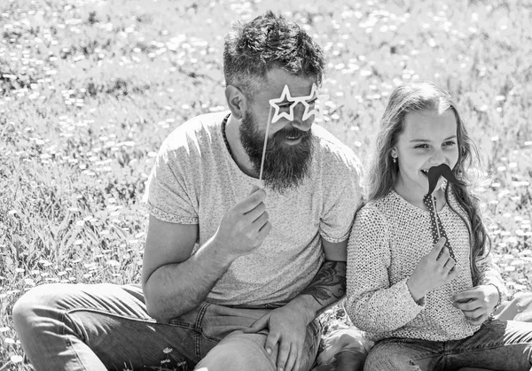 En iyi arkadaşlar kavramı. Baba ve kızı, grassplot, arka planı yeşil çimenlerin üzerinde oturur. Çocuk ve babası eyeglases, bıyık ve kravat photo booth öznitelikleri ile poz. Aile harcamak açık havada eğlence — Stok fotoğraf