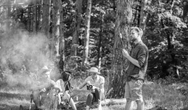 Kamera kontrol fotoğraf rahatlatıcı turistlerle. Şirket zammı piknik doğa arka plan sahip. Yaz zammını. Yürüyüşçüler ve yürüyüş yeme izlenimi paylaşımı. Ormandaki şenlik ateşi yakın arkadaşlarıyla piknik