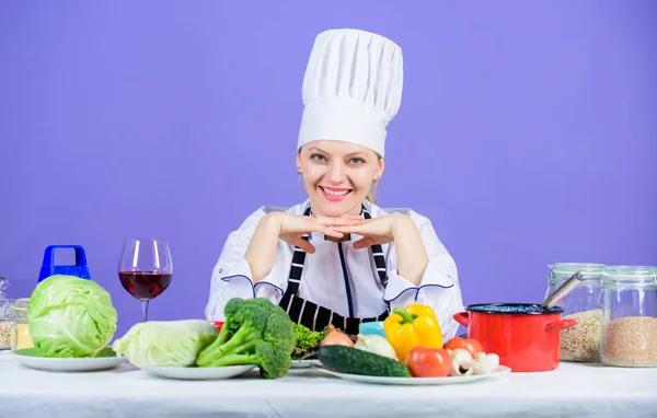 Küche Inspiration. entzückende Küchenmagd. hübsche Köchin lächelt mit Bio-Naturkost auf dem Küchentisch. glückliche Köchin sitzt in Showküche im Restaurant — Stockfoto