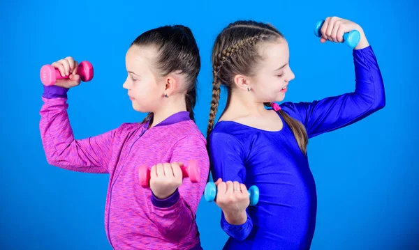 Levantamiento de pesas para músculos del cuidado del cuerpo. Cuidado de la infancia. Dieta fitness para la salud energética. Niños felices con barra. Éxito deportivo. entrenamiento de las niñas pequeñas sostienen mancuerna. concepto de cuidado corporal — Foto de Stock