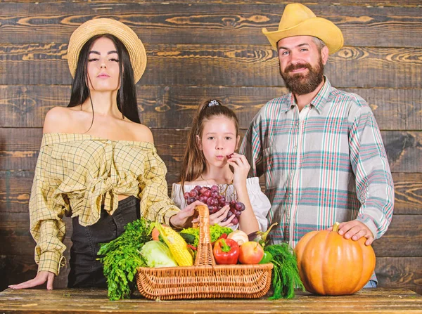 Family farmers with harvest wooden background. Parents and daughter celebrate harvest holiday pumpkin vegetables basket. Family rustic style farmers market with fall harvest. Harvest festival concept