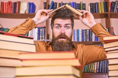 Son tarih kavramı. Öğretmen veya sakallı öğrenci kitabı, defocused çatı yapım masada oturur. Adam Kitaplığı'nda, eğitim sırasında kitaplar, kitap rafı arka plan üzerinde yığınları arasında şok yüzünde