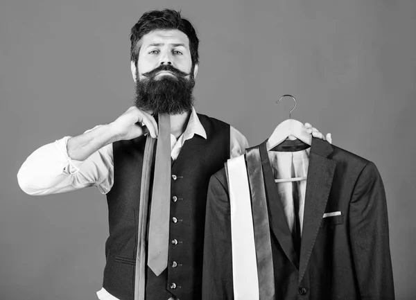 How about this tie. Brutal hipster holding colorful tie collection and suit jacket. Bearded man matching neck tie color to formal coat. Choosing a perfect tie