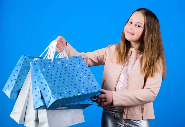 ショッピングバッグと小さな女の子。休日購入保存。キッドファッション。パッケージ付きショップアシスタント。販売と割引。幸せな子供だ贈り物を持った小さな女の子。新年のショッピング。新年プレゼント — ストック写真