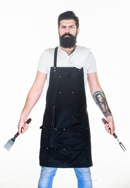 Yemek pişirmek ve servis yapmak için hazır. Elinde çatal ve spatula olan sakallı adam. Barbekü pişirme için mutfak araçları. Paslanmaz çelik mutfak gereçleri tutan hipster. Pişirme aracı seti kullanarak ızgara pişirmek