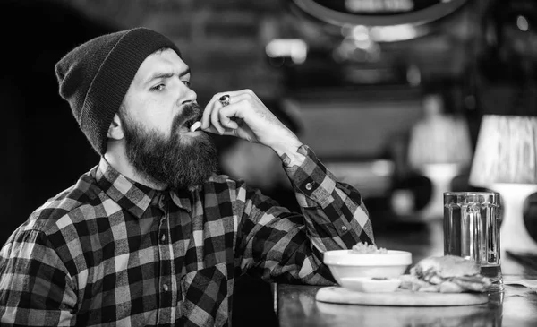 Cheat meal. High calorie food. Delicious burger concept. Enjoy taste of fresh burger. Hipster hungry man eat burger. Brutal hipster bearded man sit at bar counter. Man with beard eat burger menu