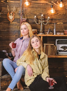 Rahatlatıcı ve mulled şarap içme kızlar. Arkadaşlar rahat kıyafetler içinde sıcak atmosferi, ahşap iç tadını çıkarın. Tatil ve tatil kavramı. Gülümseyen yüzler kareli giysiler rahatlatıcı arkadaşlar