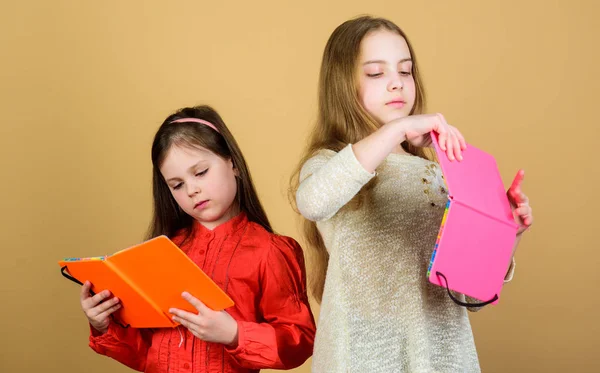 Edukacja i literatura dla dzieci. Ulubiona bajka. Siostry wybierają książki do czytania razem. Urocze dziewczyny kochają książki. Sekretny pamiętnik. Otwieranie drzwi poprzez umiejętność czytania i pisania. Dzieci dziewczyny z książek lub notesy — Zdjęcie stockowe