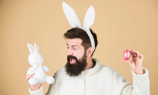 Nog kinderachtig. Vier Pasen. Guy baard hipster vrolijke Bunny met lange witte oren. Paashaas. Man draagt konijn pak spelen met speelgoed. Funny Bunny man zachte oren. PaaS activiteiten concept — Stockfoto