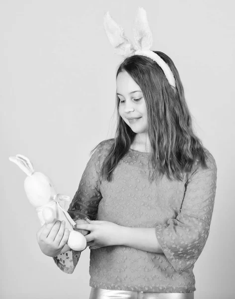 Очаровательная девушка в стиле Пасхи. Маленький ребенок с цветным яйцом и кроликом на Пасху. Малыш с пасхальным яйцом и игрушкой. Милый ребенок с пасхальным кроликом приносит яйцо — стоковое фото