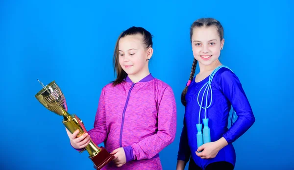 Sport achievement. Girls athletic kids celebrate victory. Athletic girls with golden goblet. Win championship. Our team first place. Children gymnasts athletic kids happy champions. Deserved award