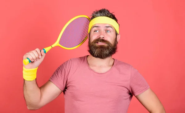 Play tennis for fun. Reach top again. Man bearded hipster wear sport outfit. Tennis player retro fashion. Tennis sport and entertainment. Athlete hipster hold tennis racket in hand red background