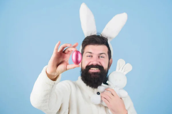 Homem barbudo usa orelhas de coelho bobas. Meu precioso. Hipster bonito coelho orelhas longas fundo azul. Coelhinho da Páscoa. A divertir-me. Coelho engraçado com barba e bigode segurar ovo rosa. Conceito de símbolo de Páscoa — Fotografia de Stock