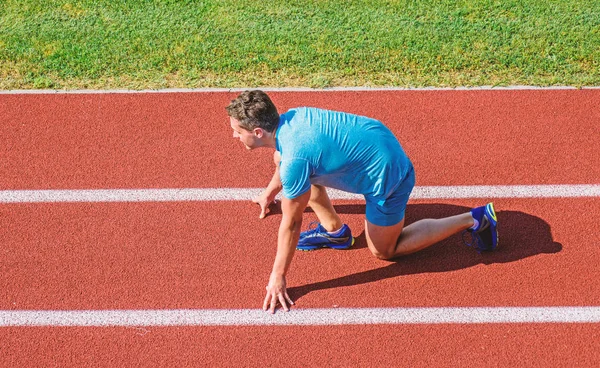 Man athlete stand low start position at stadium path. Beginning of new lifestyle habit. Runner ready to go. Athlete runner prepare to race at stadium. How to start running. Running tips for beginners — Stock Photo, Image