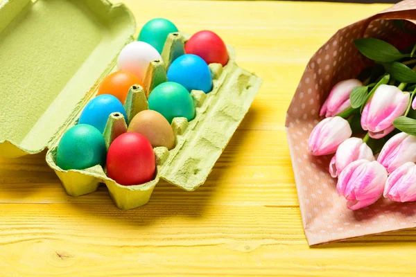 Spring holiday. Holiday celebration, preparation. Egg hunt. painted eggs in egg tray. Tulip flower bouquet. Healthy and happy holiday. Happy easter. Organic Easter