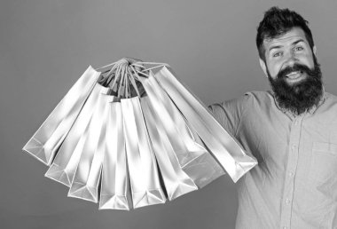 Sakal ve bıyık tutan alışveriş torbaları, kırmızı arka planı olan adam. Mutlu yüz hipster bağımlısı alışveriş veya Alışverişkoliğin. Alışveriş kavramı. Adam satış sezon indirimleri ile alışveriş