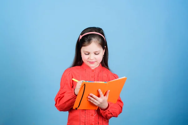 Un libro para niños. Concepto de libro. Educación para el desarrollo. Ejercicio de tarea. Escribe composición. Club de literatura. Diario personal. Estudia y aprende. Autor de poesía. Niña mantenga libro y pluma fondo azul — Foto de Stock