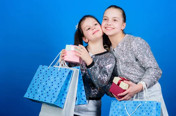 Boldog gyermekeim. Kislány nővérek díszdobozban. Kis lányok bevásárló táskák. Eladások és kedvezmények. Testvériség. Üdülési vásárlások. Gyerek divat. az üzlet asszisztense a csomagban. Mondja el véleményét! — Stock Fotó