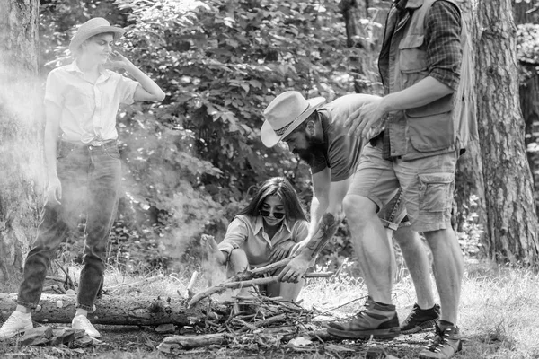 Meg dolgozik, mint a csapat tartani a máglya. Társaság ifjúsági camping erdő előkészítése máglya piknik. Adjunk hozzá néhány fa, a tűz. Vállalat barátaival vagy családjával, hogy máglya erdő jellegű háttér — Stock Fotó