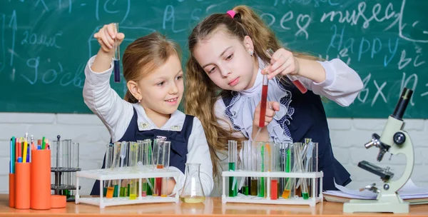 Chemia jest o reakcji. Inteligentne dzieci szkolne wykonujące test chemiczny w laboratorium. Małe uczennice uczą się chemii w czasie szkoły. Mali uczniowie posiadający probówki w laboratorium chemii — Zdjęcie stockowe