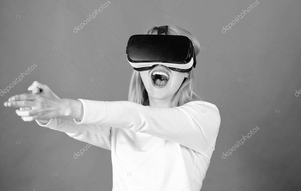 Woman using virtual reality headset. Happy young woman wearing virtual reality goggles watching movies or playing video games. Confident young woman adjusting her virtual reality headset and smiling.