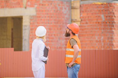 İnşaat endüstri kavramı. Kadın mühendis ve sakallı acımasız builder İnşaat ilerleme tartışmak. İnşaat Proje yönetimi. Bina endüstriyel proje. İlerleme projeyi tartışmak