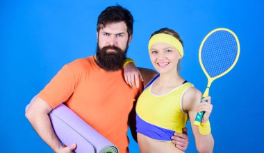 Sert tren, kolay kazanın. Mutlu kadın ve salonda sakallı adam egzersiz. Fitness mat ve tenis raketi ile sportif çift eğitim. Atletik başarı. Spor ekipmanları. Güçlü kaslar ve vücut. Tren ve kazan