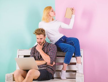 Çift farklı ilgi alanları ile birlikte vakit geçirmek. İlgi odağı. Dizüstü bilgisayar ve kitap hevesli entelektüel faaliyet kadınla olan adam. Kız ve adam entelektüel faaliyet baktılar