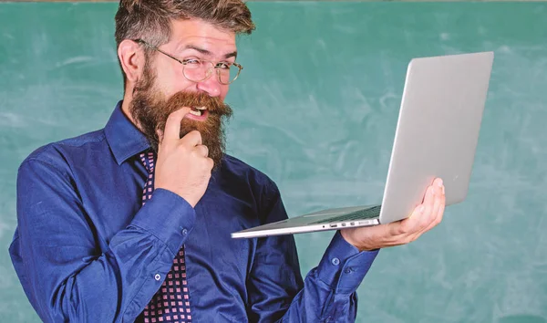 Hipster insegnante indossare occhiali e cravatta tiene computer portatile navigazione internet. Insegnante barbuto astuzia uomo moderno computer portatile navigazione internet lavagna sfondo. Interessanti informazioni. Scuola lifehack — Foto Stock