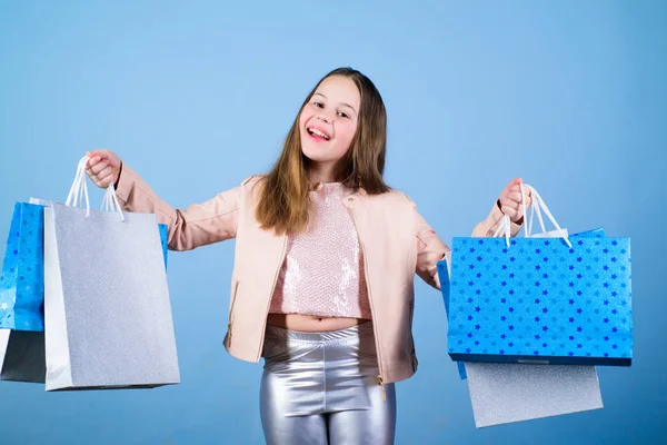 Fashion trend. Fashion shop. Little girl with bunch packages. Fashion girl customer. Happy child in shop with bags. Shopping day happiness. Buy clothes. Birthday girl shopping. Fashion boutique