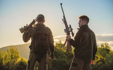 Avcılar arkadaşlar gamekeepers silahlı gökyüzü arka plan siluet. Avcı tüfekler doğa ortamı. Bu harika bir gündü. Av sezonu bitirmek. Günbatımı dağlarda zevk. Avcılar arkadaşlar eğlence keyfini çıkarın.