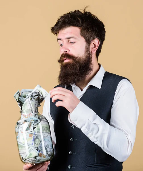 セキュリティと現金貯金。バンキングコンセプト。男髭の男は、現金貯蓄の完全な瓶を保持します。予算を設定します。経済的成功。彼はドルを貯金しているビジネスマンだ。豊かさと幸福 — ストック写真
