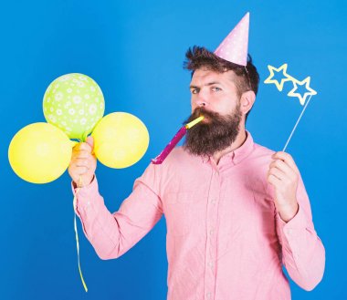 Şovmen renkli baloons ile parti, uluslararası çocuk günü çocuklar. Sakallı sanatçı gözlüklü Doğum günü şapkası parti Efes ve kağıt yıldız şekilli. Mavi arka plan üzerinde sakallı adam