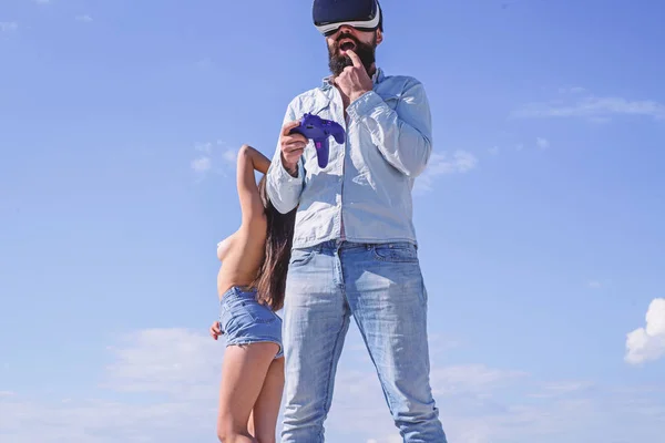 Ember szakállas csípő játszanak számítógépes szimulációs játék vr szemüveg, míg a meztelen lány stand mögött ég háttere. Cyber függőség fogalma. Gamer rabja játszani cyber valóság. Guy játék szex cyber — Stock Fotó