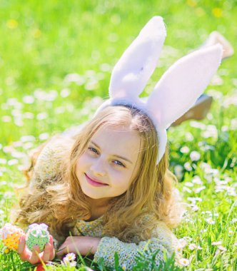 Çocuk şirin tavşan kulaklı çayır yalan. Küçük kız için bahar bahçe Paskalya yumurta Paskalya gününde avcılık. Şirin çocuk yumurta elinde çim lay. Geleneksel bunny kutluyor Bayramı kavramı