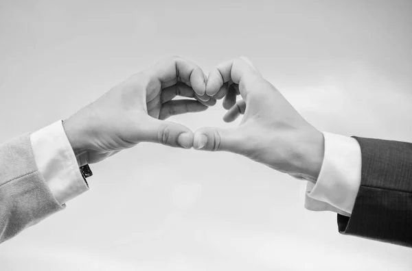 Szerelmi szimbólum fogalom. Férfi kezét a szív alakú megfelelő kézmozdulat-szimbólum a szeretet és a romantika. Kézzel szív gesztus formák alakú ujját. Kéz össze a szív alakú kék ég háttér — Stock Fotó