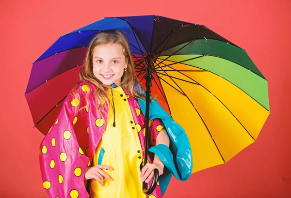 Насолоджуйтесь дощовою погодою з належним одягом. Виробництво водонепроникних аксесуарів. Водонепроникні аксесуари роблять дощовий день веселим і приємним. Дитяча дівчинка щаслива тримати барвисту парасольку носити водонепроникний плащ — стокове фото