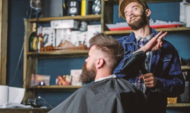 Hippi saç modeli almak istemci sakallı. Saç kurutma makinesi styling saç istemci ile neşeli yüzündeki berber. Kuaför saç kurutma makinesi ile saç modeli sakallı adam, salon arka plan için çalışır. Tasarım konsepti