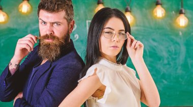 Sakal ve gözlük stand sırt sırta, kara tahta arka plan öğretmen olan adam. Bayan ve birlikte okulda çalışan hippi. Ekip çalışması kavramı. Öğretmen ve öğretmen rahat görünüyor