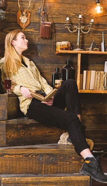 Bayan kareli giysiler içinde sakin yüzünde rahat görünüyor. Gevşeme kavramı. Kız öğrenci kitap ve mulled şarap ile rahatlatıcı. Ahşap vintage iç kitap ile gündelik kıyafeti kız oturur — Stok fotoğraf