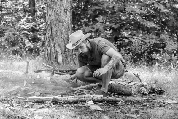 Disporre i ramoscelli del bosco o bastoni di legno in piedi come una piramide e posizionare le foglie sotto. Guida definitiva ai falò. Come costruire falò all'aperto. Uomo cappello di paglia prepara falò nella foresta — Foto Stock