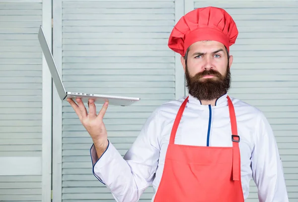 Lieferservice. Chef-Laptop in der Küche. Kochschule. Hipster in Hut und Schürze kaufen Produkte online. Online einkaufen. Mann Koch Suche online Zutaten Kochen von Lebensmitteln. Lebensmittelgeschäft online — Stockfoto